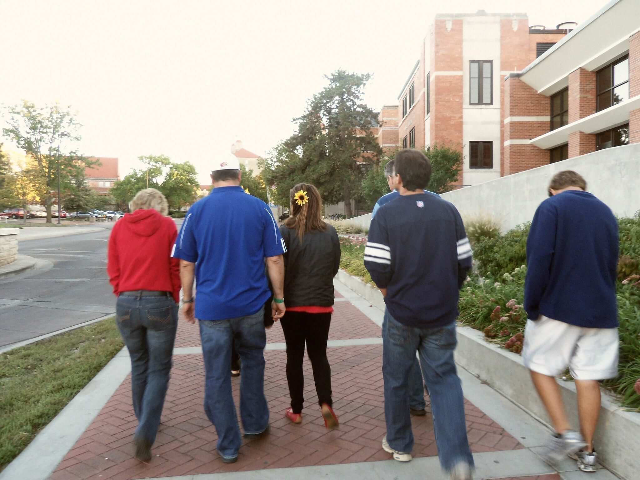 family of five walking on sidewalk in shade