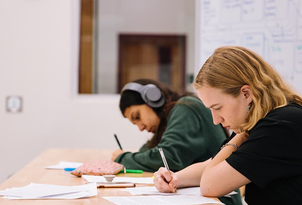 two students writing test at table