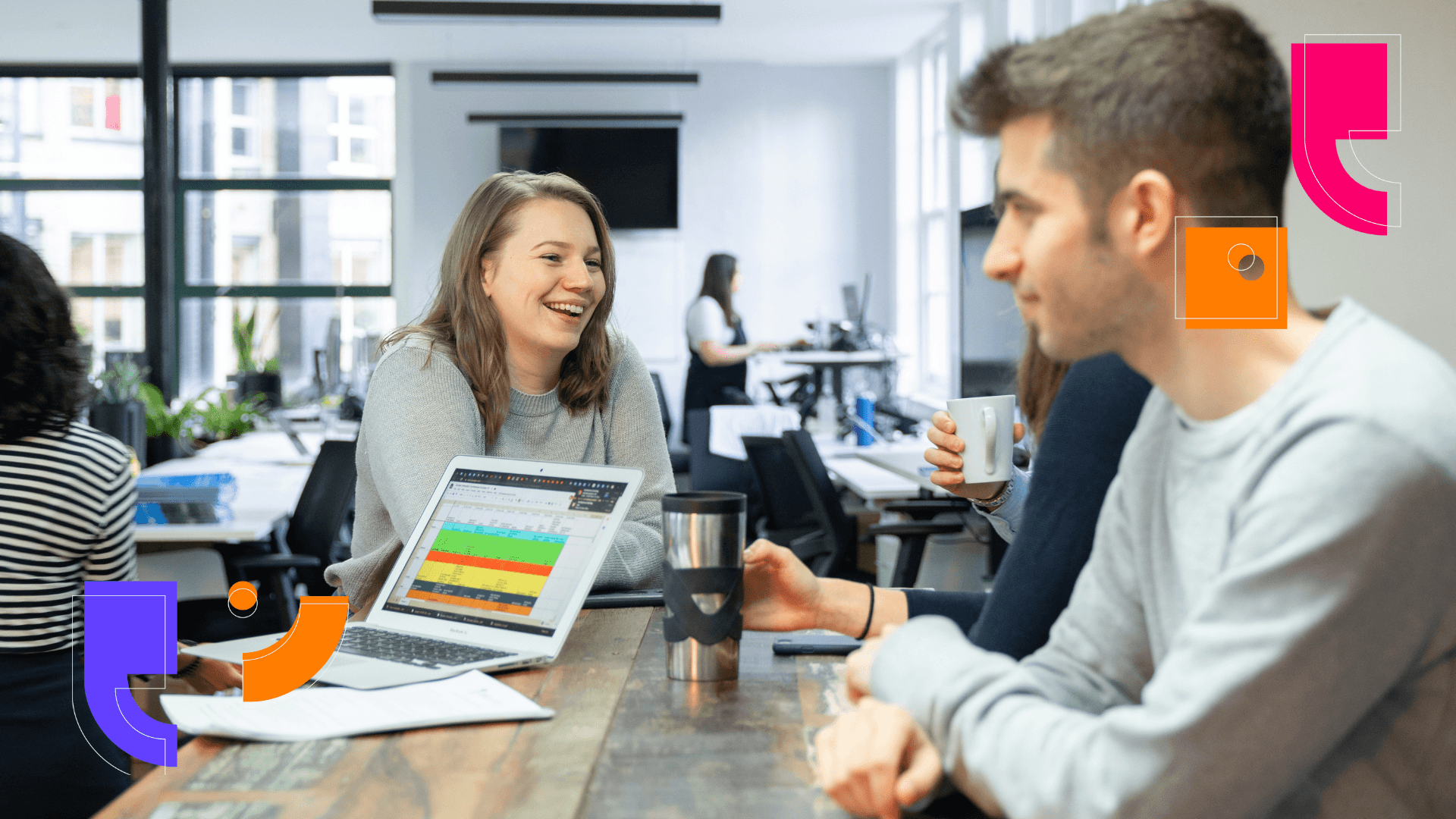 crowded workdesk with two workers smiling looking at one another