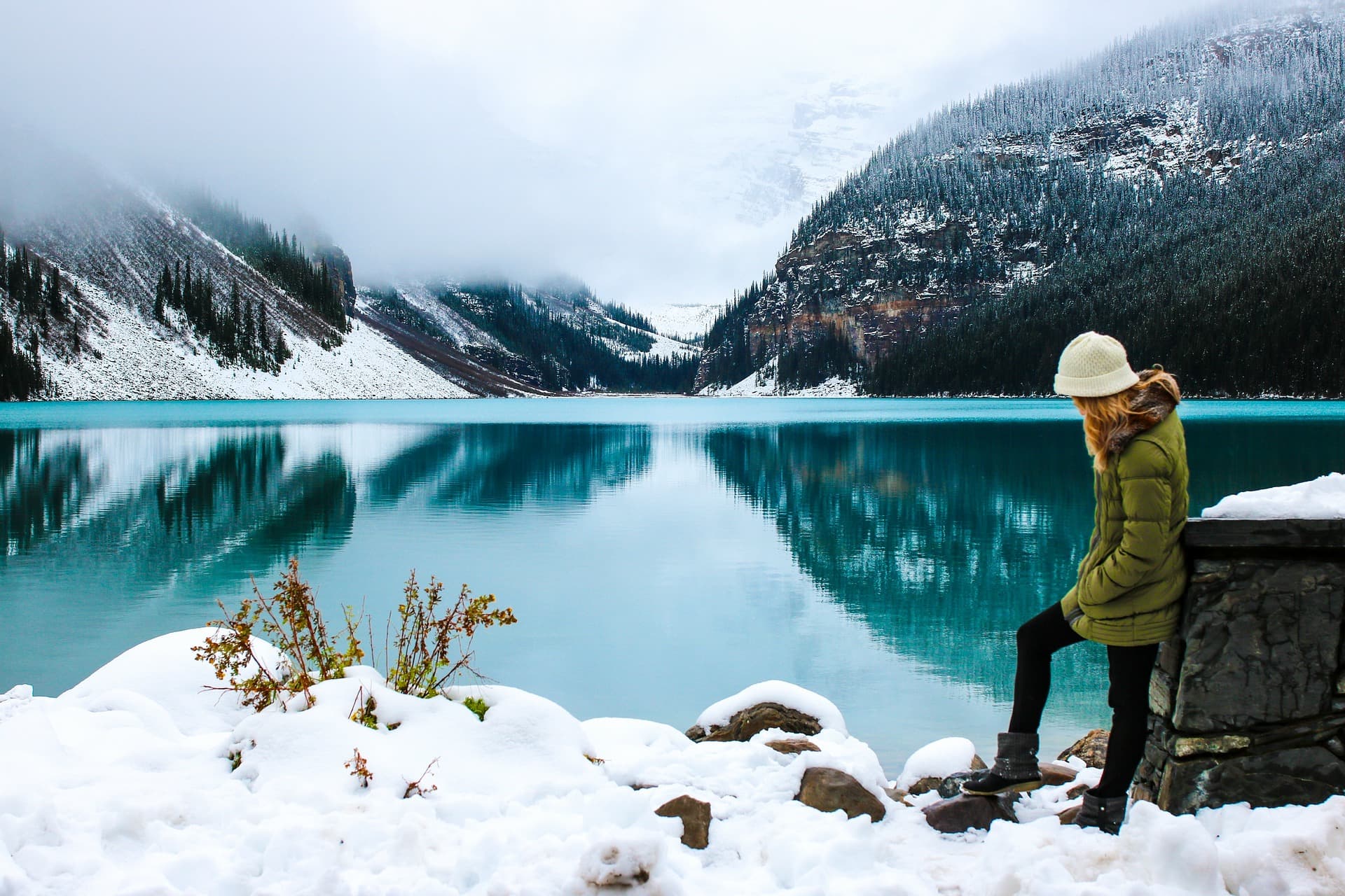 woman standing on shoreline of Lake Louise, Canada, in snow