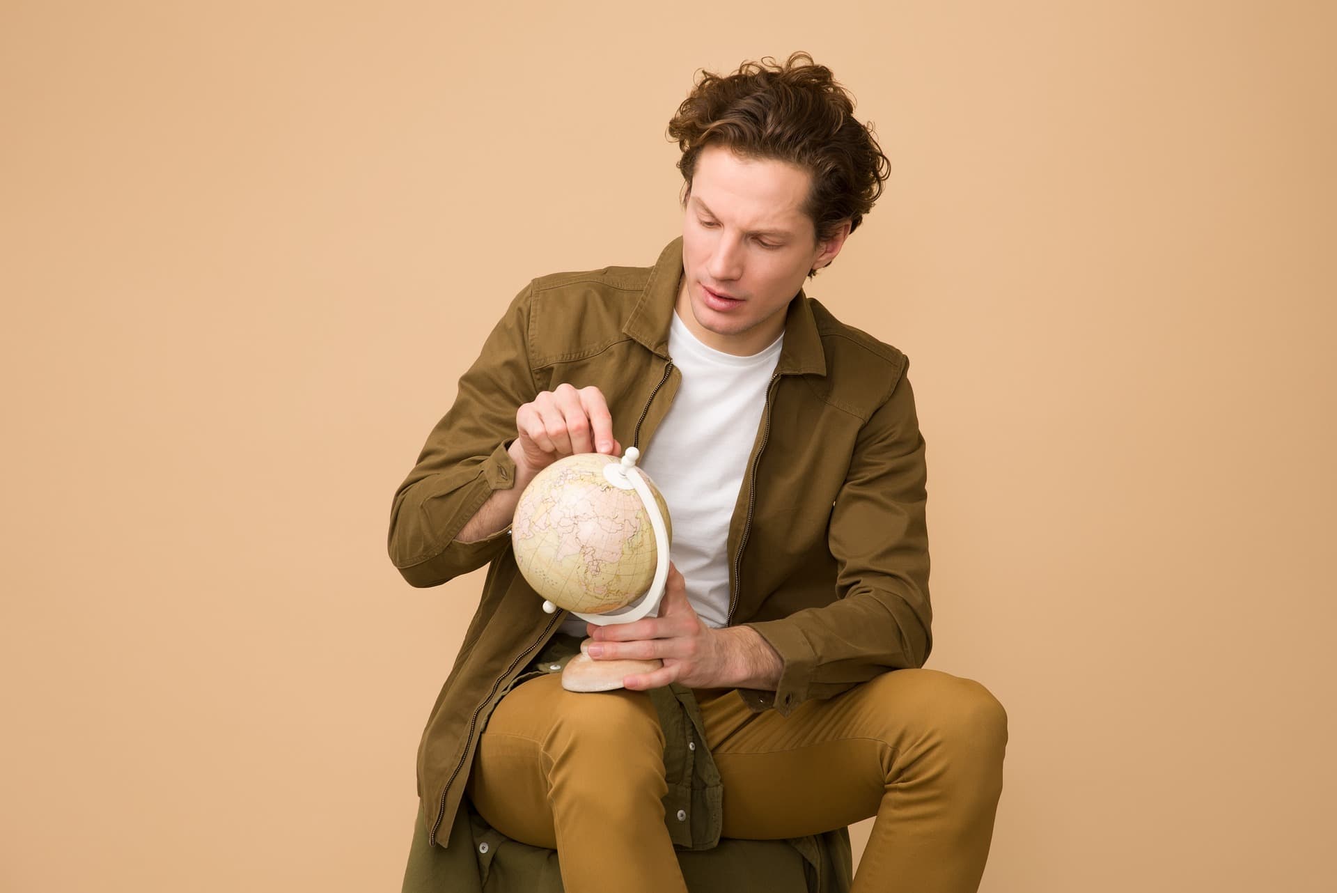 man wearing coat pointing at globe