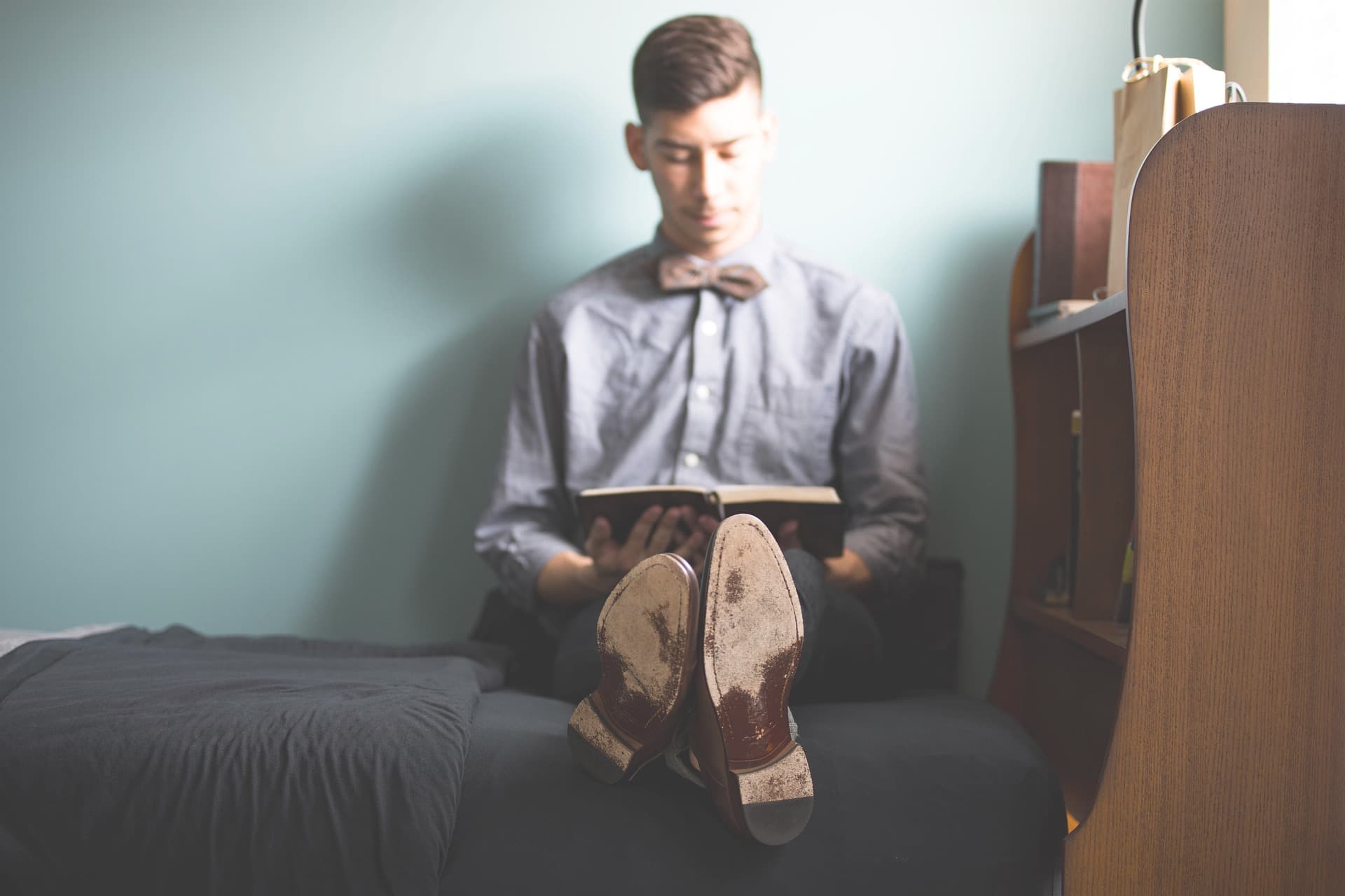 man sitting on bed reading