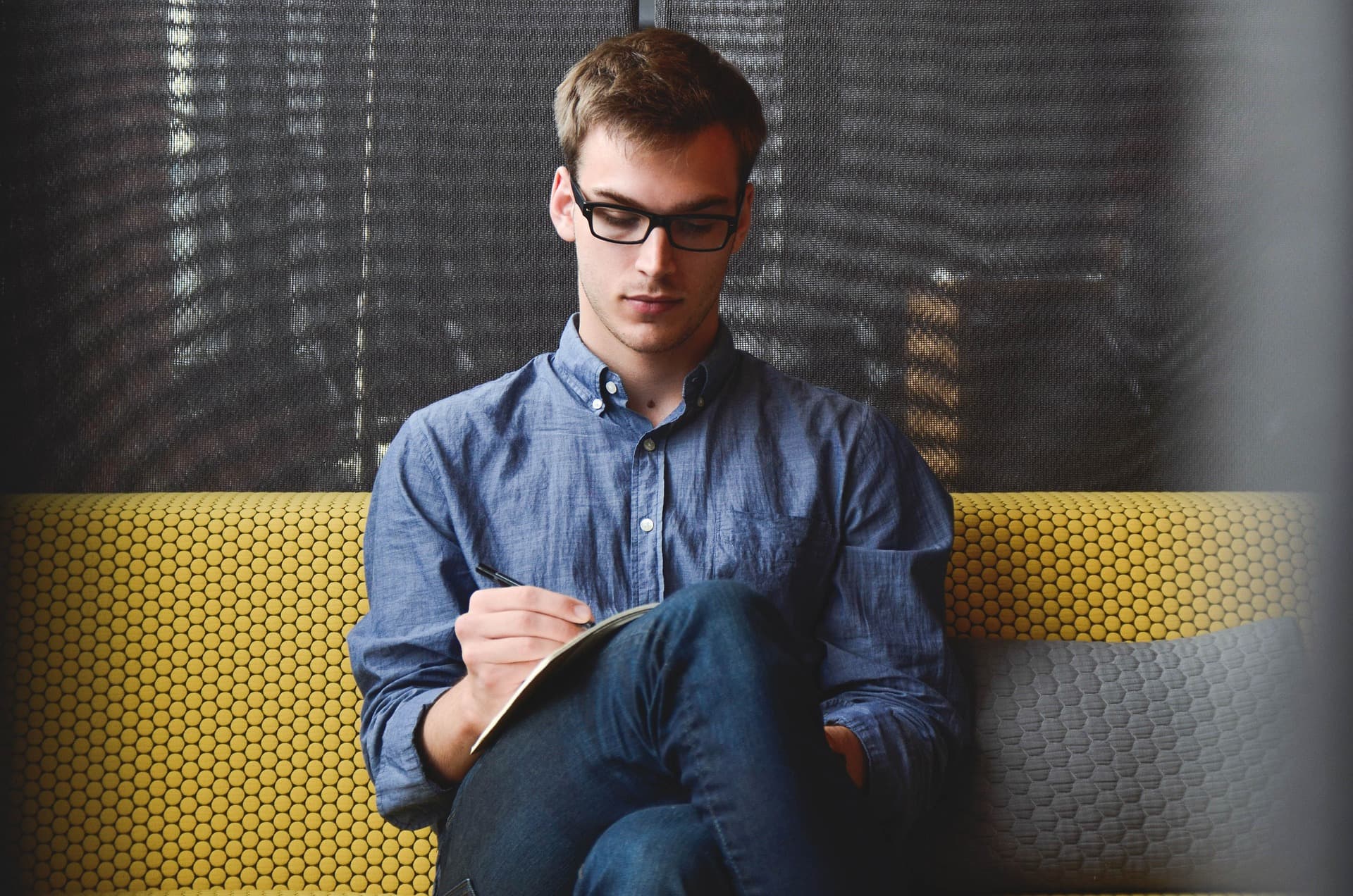 man sitting and writing in notebook