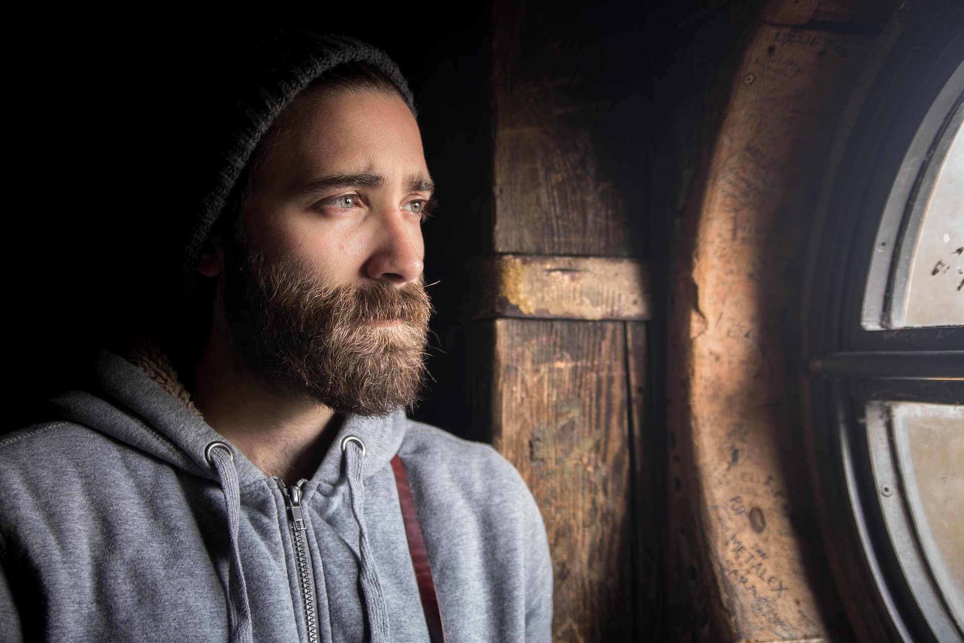 man wearing toque looking out window