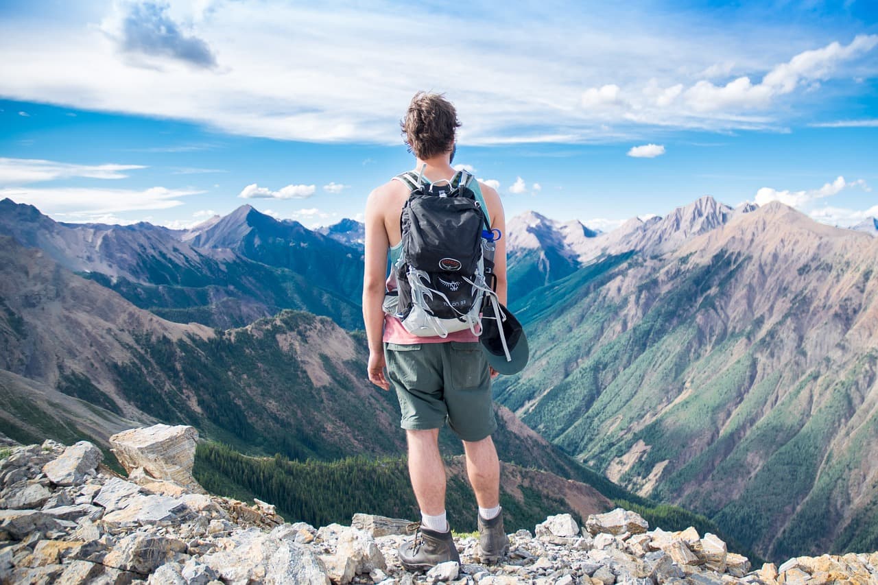 man standing at edge of mountain cliff overlooking valley