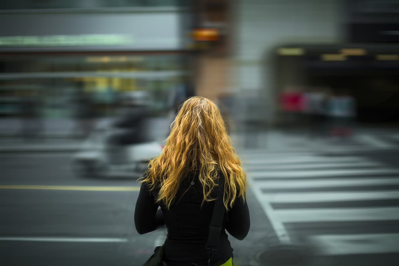 girl waiting for traffic looking into busy city street