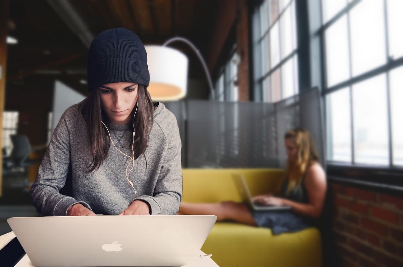 woman working on laptop with another woman working off laptop in background