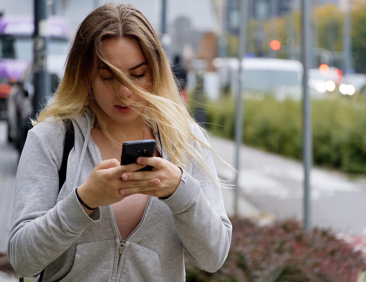 woman outside typing on smartphone