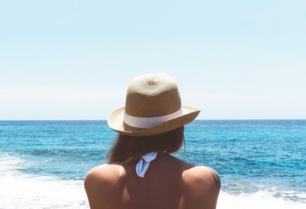 Woman wearing hat looking across ocean