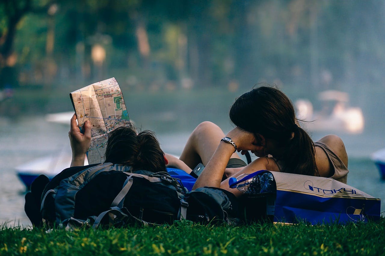 couple reading map lying down in park